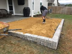 a man is shoveling sand in the yard