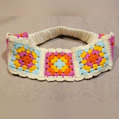 a crocheted headband with multicolored squares on it sitting on a table