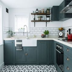 a kitchen with green cabinets and white counter tops, black and white tile flooring