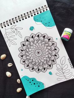 a spiral notebook with an image of a flower and leaves on it next to some sea shells