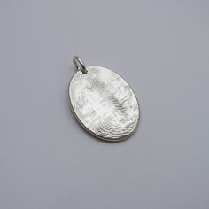 Keep your loved one with you always, with this classic oval fingerprint pendant. Handcrafted in solid sterling silver, this pendant features a beautiful oval design that is elegant and simple. The intricate details of your fingerprint are captured with exceptional precision using my perfected techniques and processes along with state-of-the-art technology, ensuring that every pendant is a true work of art and one of a kind. The pendant is available in a range of sizes, so you can choose the perf Hand Stamped Sterling Silver Oval Pendant, Sterling Silver Hand Stamped Oval Pendant Jewelry, Silver Hand Stamped Oval Pendant Jewelry, Silver Oval Pendant Jewelry Hand Stamped, Silver Stamped Oval Pendant Jewelry, Silver Oval Pendant Jewelry With Engraving Option, Silver Jewelry With Engraving Option, Oval Pendant, Fingerprint Jewelry Memorial, Fingerprint Necklace