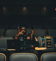 a man sitting in an auditorium using a laptop