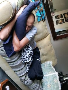 a man and woman hugging each other while sitting on top of a couch in a living room