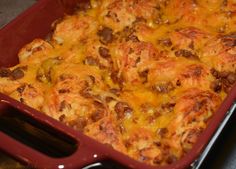 a red casserole dish filled with cheese and meat covered in melted cheeses