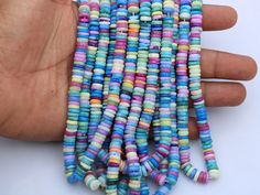 a hand is holding several multicolored beads