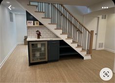 an empty kitchen with stairs leading up to the second floor and a wine cooler in the middle