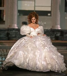 a woman in a white dress is walking down the runway