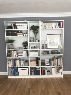 a white bookcase filled with lots of books on top of a hard wood floor