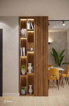 an open bookcase in the middle of a room with yellow chairs and plants on it