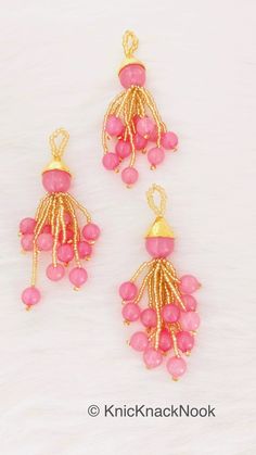 two pink beads are hanging from gold plated earwires on a white background