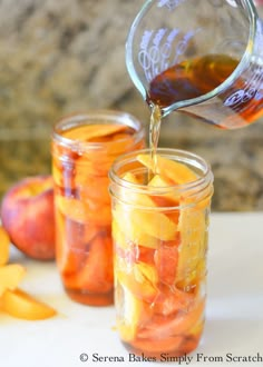 someone pours syrup into jars filled with sliced peaches and orange peels on a cutting board