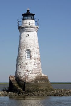 a light house sitting on top of a rock in the middle of a body of water