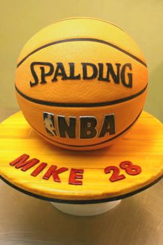 a cake made to look like a basketball sitting on top of a wooden plate that says spalding nba mike 29