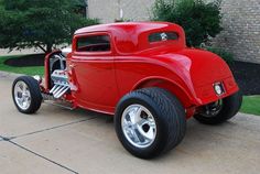 an old red car parked in front of a brick building