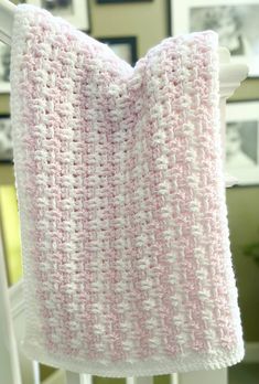 a pink and white crocheted blanket hanging from a chair