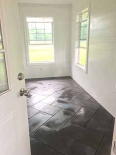 an empty room with two windows and tile flooring on the outside side of the room