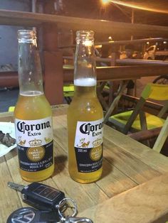 two bottles of corona beer sitting on top of a table next to a car key