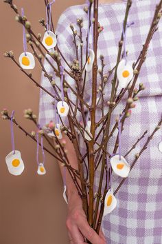 a woman holding a branch with eggs on it