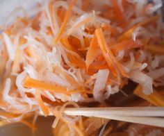 shredded carrots and onions in a bowl with chopsticks