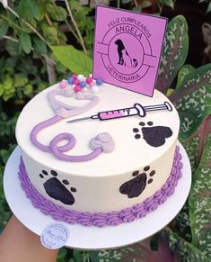 a white cake with purple icing and black paw prints on the side, topped with a pink card