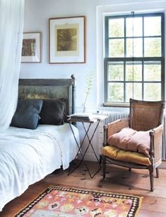 a bed room with a neatly made bed next to a window and a rug on the floor