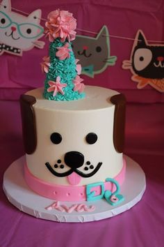 a birthday cake with a dog and cat decoration on it's top, sitting on a table