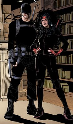 a man and woman standing next to each other in front of bookshelves wearing black outfits