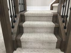 the carpeted stairs are lined with black iron handrails and wood balconies