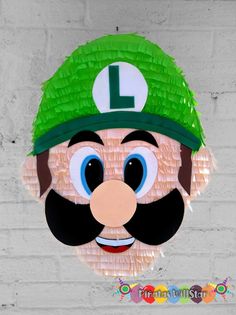 a paper mario bros mask hanging on a brick wall with the letter l painted on it