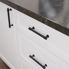 a kitchen counter with black handles and white cabinets