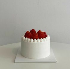 a white cake topped with strawberries on top of a table