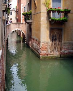 a narrow canal runs between two buildings with flowers on the balconies above them