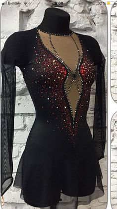 the back of a black dress with red and gold sequins on it, next to a white brick wall