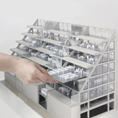 a hand is reaching for a model of a building