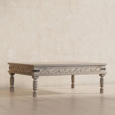 a wooden table sitting on top of a hard wood floor next to a white wall