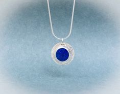 This sterling silver 'coin' pendant features a round, flat Lapis Lazuli Gemstone that is an amazing even shade of celestial blue.  We styled this pendant with two sterling silver discs - the back one is textured and is .80 inches round. The disc with the Lapis Lazuli is a bit larger than one half inch. This modern, playful, Lapis Lazuli necklace is on an Italian-made sterling silver snake chain with lobster clasp. At checkout, you have a choice of a 16 or 18 inch length. A great gift for Lapis l Blue Coin Pendant Jewelry, Blue Coin Pendant Jewelry As Gift, Blue Coin Pendant Jewelry For Gifts, Cabin Studio, Celestial Blue, Lapis Lazuli Pendant, Lapis Lazuli Necklace, Lapis Lazuli Gemstone, Silver Snake Chain