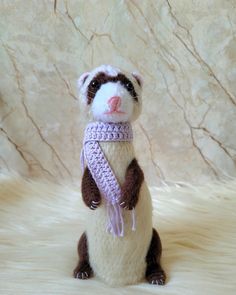 a stuffed animal with a scarf around it's neck sitting on a fur surface