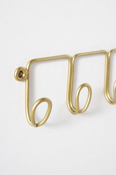 three gold hooks hang on a white wall