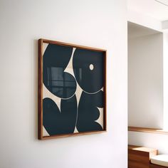 an abstract painting hangs on the wall next to a bench in a room with white walls