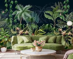 a living room with green couches and tropical plants on the wall behind them in front of a coffee table