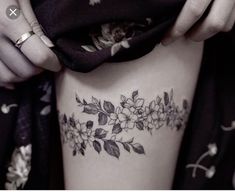 a close up of a woman's thigh with flowers and leaves tattooed on it