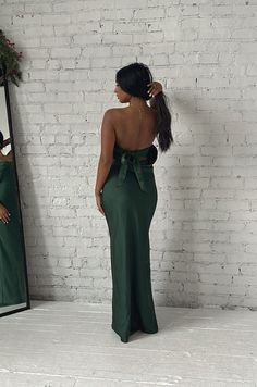 This Emerald Green Maxi Dress will make you feel elegant and special. Crafted from luxuriously smooth satin silky, the dress features a strapless silhouette with a cowl back and a waisted tie. The long length flatters any figure and makes this dress perfect for a formal occasion. emerald green strapless dramatic cowl back back bow tie relaxed fit long length 100% polyester model is wearing a small Floor-length Satin Strapless Dress For Party, Fitted Maxi Dress With Bow Tie Back For Party, Backless Satin Evening Maxi Dress, Evening Strapless Fitted Dress With Bow Tie Back, Elegant Fitted Maxi Dress With Bow Tie Back, Fitted Strapless Dress With Bow Tie Back For Evening, Party Evening Dress With Tie Back And Fitted Bodice, Green Satin Finish Evening Dress For Party, Backless Satin Maxi Dress For Prom Season