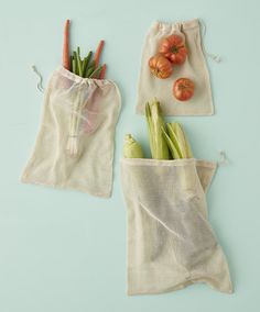 two bags filled with vegetables sitting on top of a blue table next to each other