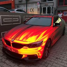 a car with flames painted on it parked in front of a building