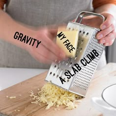 a person grating cheese with a grater on a wooden cutting board next to a white plate