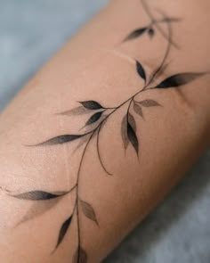 a close up of a person's leg with leaves on it and the bottom part of her arm