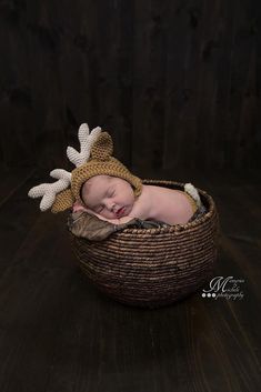 a newborn baby wearing a crocheted hat and sleeping in a wicker basket