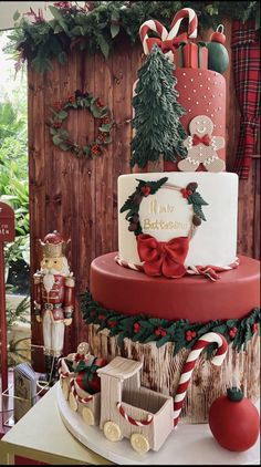 a three tiered christmas cake decorated with candy canes and bows, sits on a table next to other holiday decorations