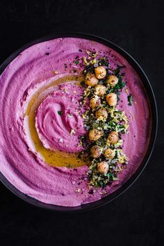 a bowl filled with pink hummus and garnish