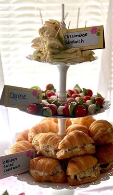 three tiered trays with sandwiches and croissants on them are displayed